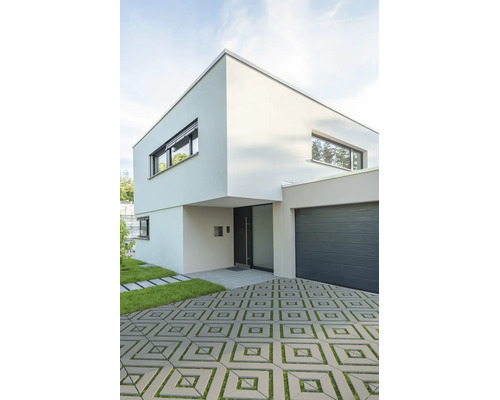 Maison moderne à deux étages avec toit plat, garage intégré et allée pavée avec joints en gazon.