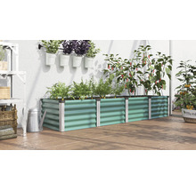 Un potager surélevé rectangulaire en métal dans une serre avec diverses plantes, herbes et légumes.