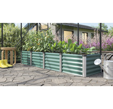 Carré potager rectangulaire en métal à structure ondulée planté de tomates et de laitue dans une serre sur une terrasse pavée.