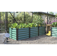 Potager surélevé rectangulaire en métal avec structure ondulée dans une serre avec des plantes et des outils de jardin sur une terrasse.