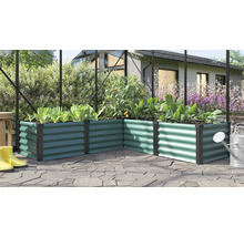 Jardinière surélevée en angle en métal ondulé dans une serre avec des plantes et un arrosoir sur une terrasse.