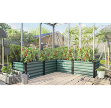 Jardinière surélevée en angle en métal dans une serre avec des plants de tomates sur une terrasse en bois.