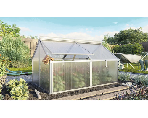 Châssis de forçage en aluminium avec plaques alvéolaires dans un jardin ensoleillé avec des outils de jardinage et des plantes en arrière-plan.