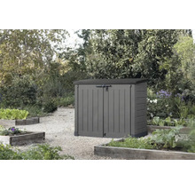 Coffre de jardin en plastique avec double porte pour rangement dans le jardin posé sur une allée de gravier devant des plates bandes