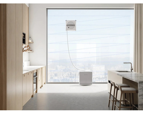 Robot laveur de vitres en action sur une grande baie vitrée dans une cuisine moderne et lumineuse.