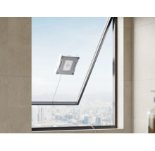Un robot laveur de vitres nettoie une grande vitre avec vue sur une ligne d'horizon urbaine.