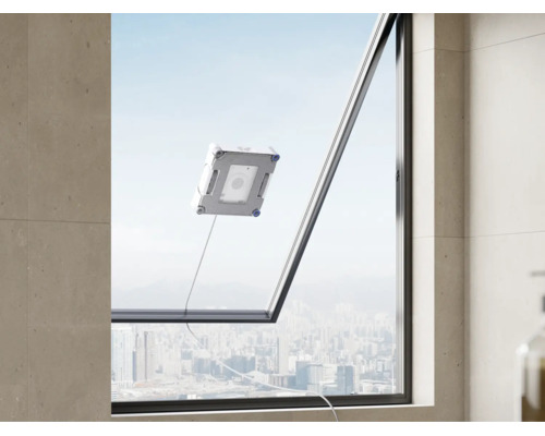 Un robot laveur de vitres nettoie une grande vitre avec vue sur une ligne d'horizon urbaine.