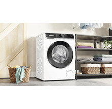 Lave-linge Bosch dans une buanderie moderne avec panier, étagères et linge plié.