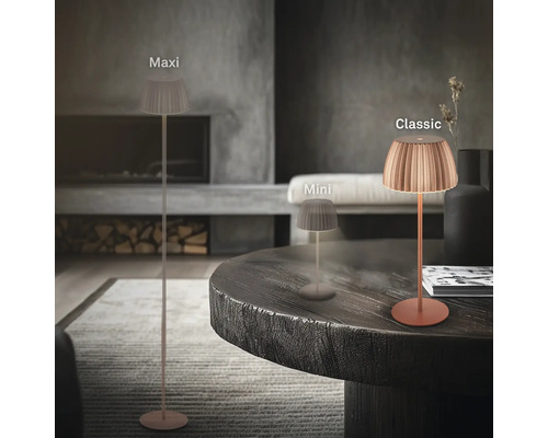Drei verschiedene Größen der LED Tisch und Stehleuchte mit plissiertem Schirm in einem modern eingerichteten Wohnzimmer mit Kamin.