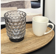 LED Tischleuchte aus Glas mit strukturierter Oberfläche auf einem Holztablett neben einer Tasse.
