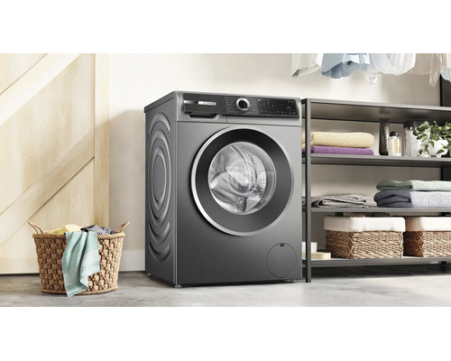 Un lave-linge Bosch est installé dans une buanderie moderne à côté d'une étagère à linge et d'un panier en osier.