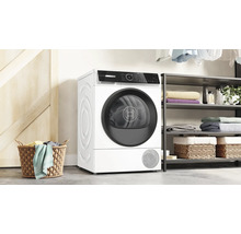 Sèche-linge Bosch dans une buanderie moderne à côté d'une étagère avec des serviettes et un panier à linge.