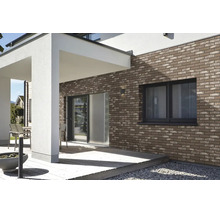 Moderne Hausfassade mit Klinkerriemchen an einer Terrasse mit Holzbelag und einem weißen Vordach.