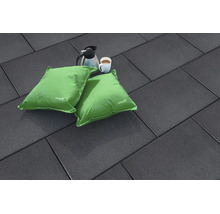 Dalles de terrasse rectangulaires sombres avec deux coussins verts, une cafetière et une tasse de café posées sur une surface plane.