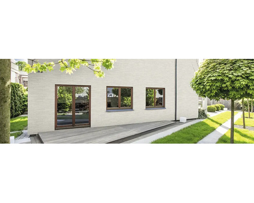 Moderne Hausfassade aus hellen Verblendern mit bodentiefen Fenstern und Holzterrasse vor einem gepflegten Garten.
