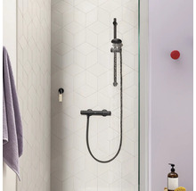 Duschsystem mit Thermostatarmatur an einer Wand mit sechseckigen Fliesen in einem modernen Badezimmer.