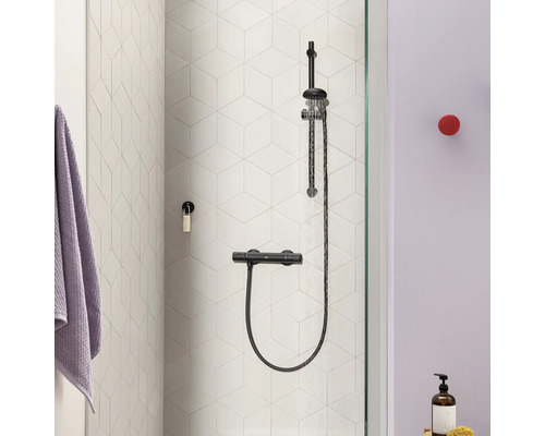 Duschsystem mit Thermostatarmatur an einer Wand mit sechseckigen Fliesen in einem modernen Badezimmer.