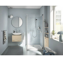 Modernes Badezimmer mit Dusche mit Glastür und Duscharmatur, wandhängendem Waschtisch, rundem Spiegel und gefliesten Wänden in heller Gestaltung.