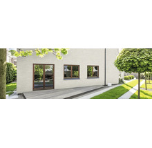 Moderne Hausfassade aus hellen Verblendern mit bodentiefen Fenstern und Holzterrasse vor einem gepflegten Garten.