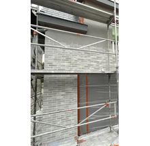 Fassade mit Riemchen verblendet während der Sanierung mit Baugerüst vor dem Haus.