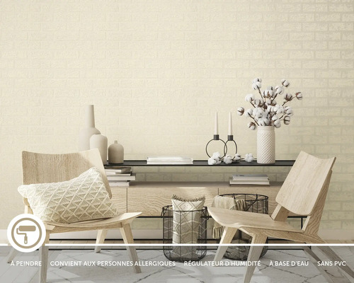 Salon avec papier peint intissé beige aspect brique, combiné avec des chaises en bois clair, une commode moderne et des accessoires décoratifs.