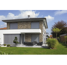 Maison individuelle moderne avec façade en brique et terrasse, équipée de volets roulants et de stores extérieurs gris.