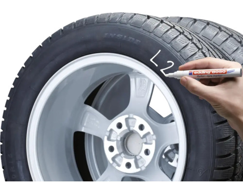 Une main marque un pneu de voiture avec un marqueur pour pneus Edding 8050.