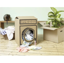 Eine aus einem Pappkarton gebastelte Waschmaschine auf einem Holzboden mit Kleidung und einem Edding Stift daneben.
