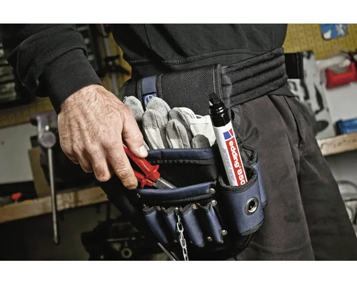 Handwerker mit einer Werkzeuggürteltasche ausgestattet mit Arbeitshandschuhen und einem Edding Permanentmarker im Werkstattumfeld.