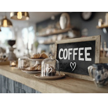 Un comptoir de cafe avec un tableau ecrit Coffee et une petite cloche en verre avec une patisserie sur le bar.
