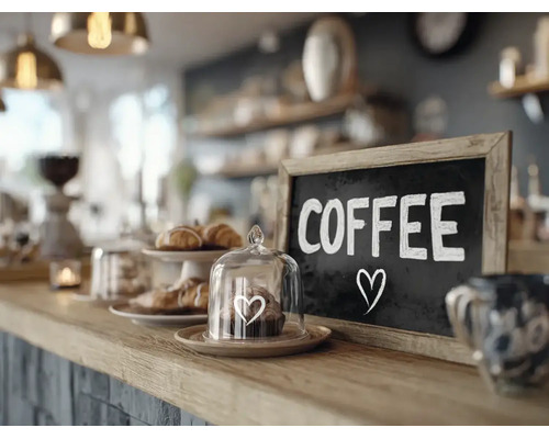 Un comptoir de cafe avec un tableau ecrit Coffee et une petite cloche en verre avec une patisserie sur le bar.