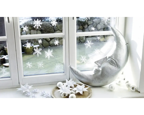 Décoration de Noël sur un rebord de fenêtre avec un croissant de lune argenté, des étoiles en papier et des autocollants de fenêtre.