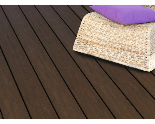 Dunkle Terrassendielen aus Holz mit einem geflochtenen Korbsessel und einem lila Kissen auf einer Terrasse.