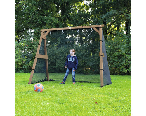 Un garçon joue au football devant un but de football en bois avec filet de protection intégré dans un jardin.