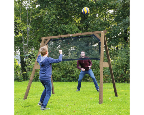Un enfant et un adulte jouent avec un ballon autour d'une structure de jeu en bois avec filet dans un jardin.