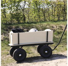Une charrette en bois avec quatre grands pneus pneumatiques est garée sur un chemin forestier et chargée d'un ballon et d'un sac.