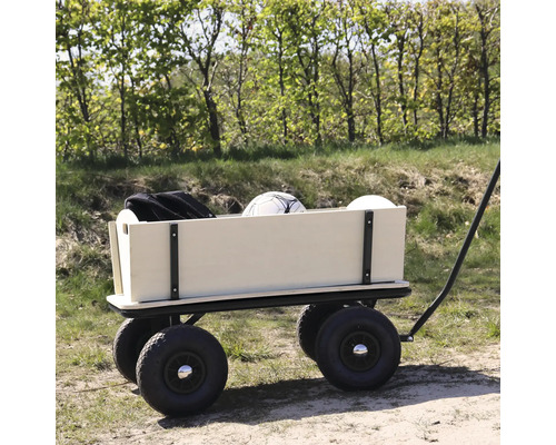 Une charrette en bois avec quatre grands pneus pneumatiques est garée sur un chemin forestier et chargée d'un ballon et d'un sac.