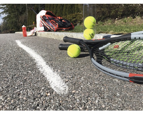 Raquettes de tennis, balles de tennis, sac de tennis et gourde sur asphalte