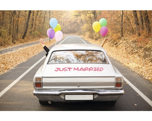 Voiture argentée avec inscription fraîchement mariée et ballons sur une route