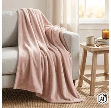 Un plaid doux est posé de manière décorative sur un canapé gris à côté d une table d appoint en bois dans un salon confortablement aménagé. (Image AI modified or generated)