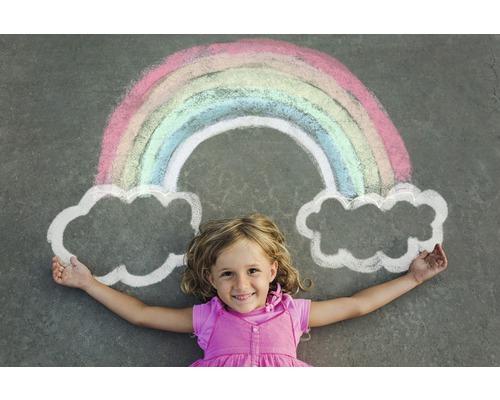 Un enfant est allongé sous un arc-en-ciel et des nuages dessinés à la craie