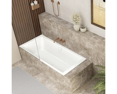 Baignoire rectangulaire moderne avec paroi de douche encastrée dans une niche revêtue de carreaux de marbre avec robinetterie encastrée.
