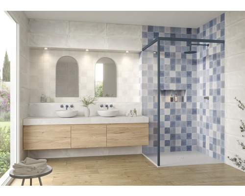 Badezimmer mit Waschtisch, Spiegeln und begehbarer Dusche mit blauen Fliesen.