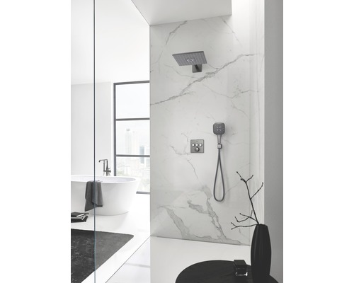 Salle de bain avec mur en marbre, douche avec pomme de tête et douchette, et baignoire îlot