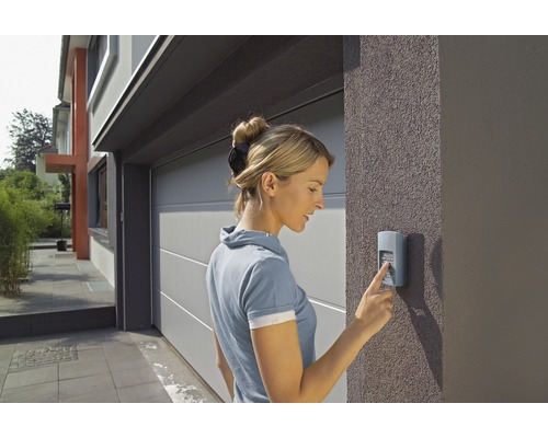 Une femme actionne un bouton pour une porte de garage.