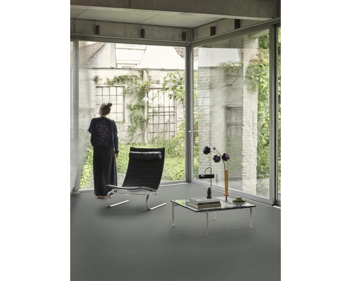 Heller Raum mit großem Fenster, Sessel und Couchtisch auf einem Bodenbelag