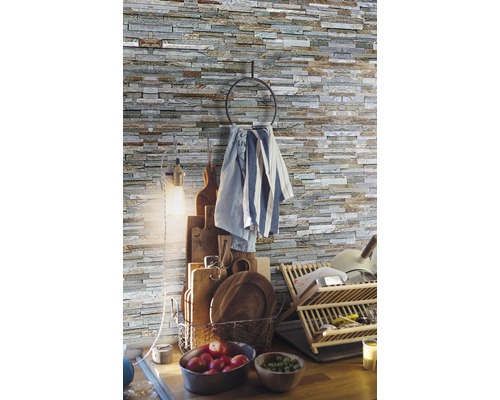 Scène de cuisine avec pierres décoratives au mur, porte-torchon, planches à découper, panier à vaisselle et fruits frais