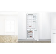 Réfrigérateur encastrable avec porte ouverte et plusieurs étagères pour le stockage des aliments dans une cuisine lumineuse.