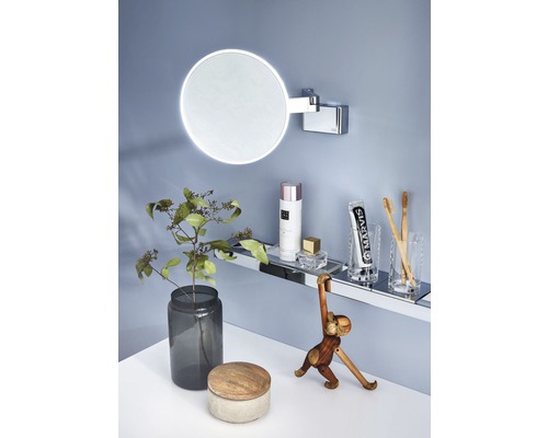 Badezimmer Szene mit beleuchtetem Spiegel, Regal und Dekorationsartikeln.