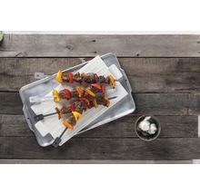 Deux brochettes de viande avec des poivrons sur un plateau et de l''ail dans un bol